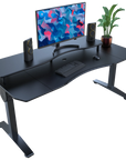 Black rectangular desk with computer setup including a monitor, keyboard, speakers, and a plant on a white background.
